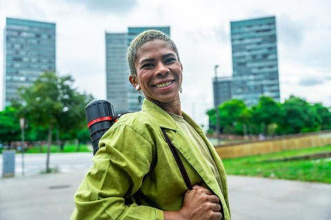 Urban architect smiling confidently with drawing tube on shoulder strap, standing in front of