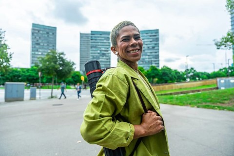 Smiling woman architect carrying a drawing tube on her shoulder. Walking confidently through a