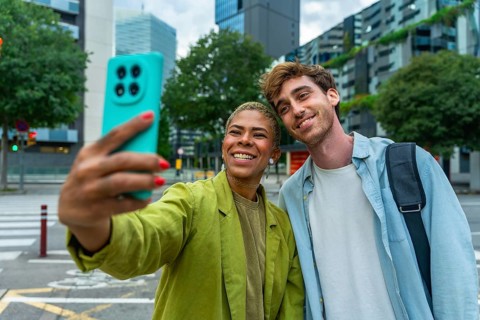 Diverse couple smiling and taking a selfie with a smartphone, sharing a moment of connection and