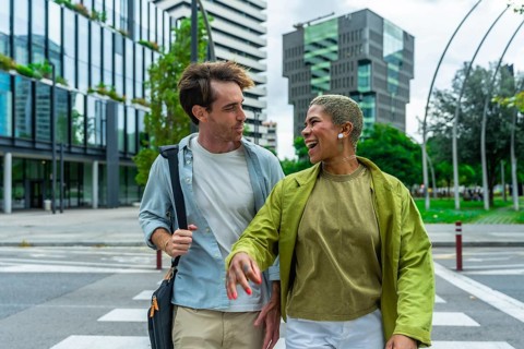 Engaging diverse colleagues walking across a city crosswalk, sharing a moment of laughter while