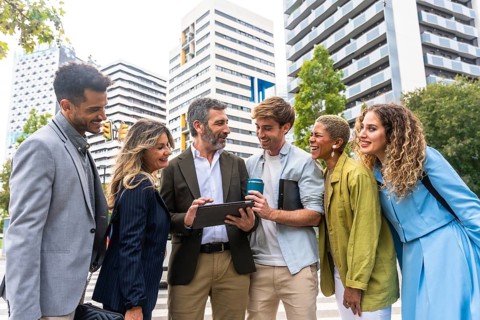 Diverse business professionals smiling and communicating, looking at a digital tablet together on a