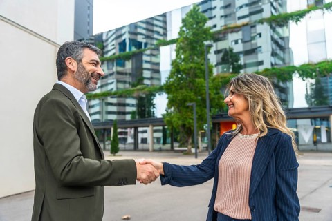 Two business colleagues exchanging a handshake in a modern city environment, symbolizing a