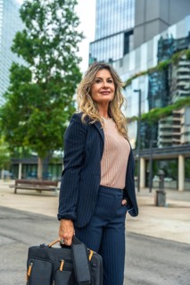 Confident businesswoman wearing a pinstripe suit, holding a briefcase and looking forward, standing