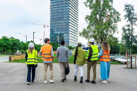Diverse team of engineers, architects, and business executives standing with backs to camera,