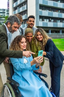 Multi ethnic business team smiling and reviewing a corporate project on a smartphone held by a