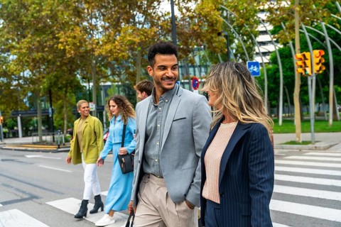 Group of executives and colleagues communicating while crossing a busy urban street, representing
