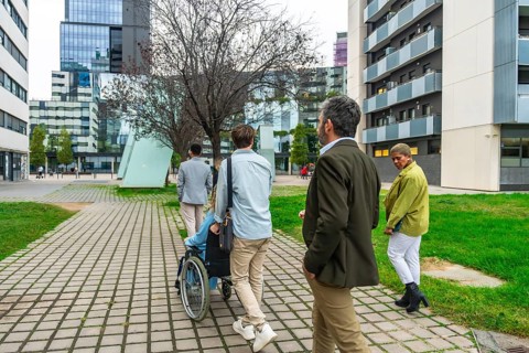 Diverse group of colleagues walking on a paved pathway through a modern city district, one person