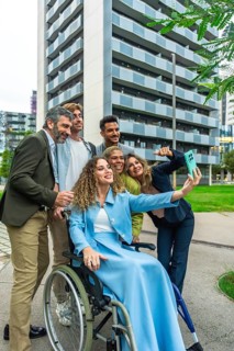 Group of multi ethnic colleagues and friends, including a woman in a wheelchair, smiling and taking