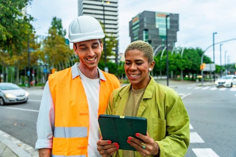 Construction manager man in hard hat and woman architect reviewing building plans on a digital