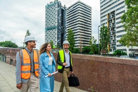 Diverse team of engineers and executives wearing safety vests and hard hats walking outdoors in a