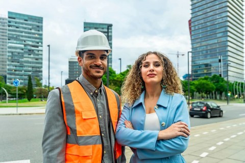 Building professionals smiling and standing on a city street, conveying teamwork, collaboration,