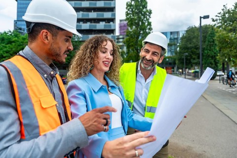 Diverse group of construction professionals discussing architecture plans and collaborating on a
