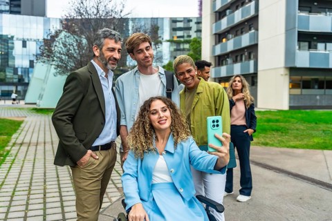 Diverse business team, including a woman in a wheelchair, smiling and taking a cheerful outdoor