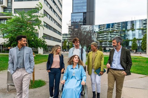 Diverse group of smiling business people, including a woman in a wheelchair, actively collaborating