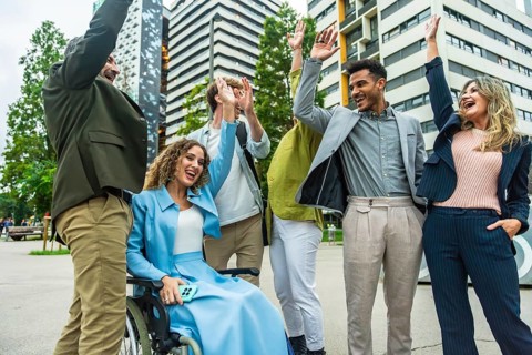 Diverse business colleagues including a woman in a wheelchair cheering and doing high fives