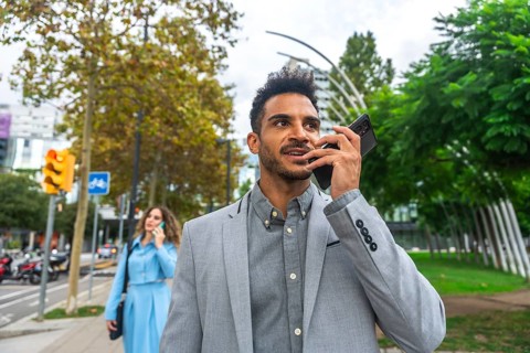 Confident young business professional communicating on a mobile phone, using its speaker function