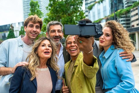 Diverse group of smiling business professionals and executives taking a happy selfie with a camera