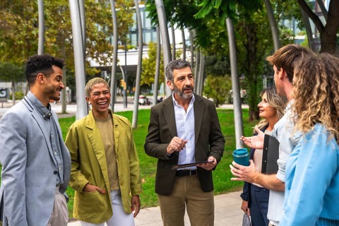 Diverse group of business professionals meeting, exchanging ideas, and smiling outdoors in a modern