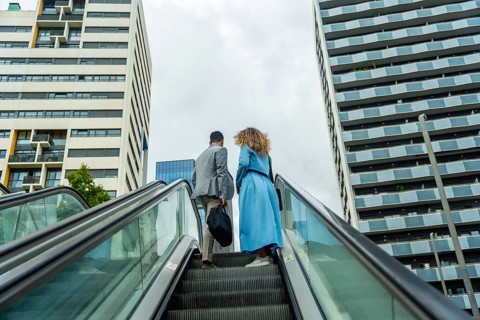 Business professionals ascending an outdoor escalator in a modern urban environment, symbolizing