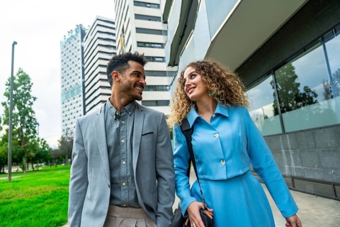 Diverse business professionals walking and smiling in a modern urban setting, conveying teamwork,