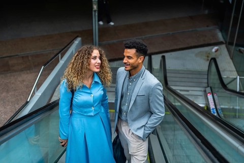 Two diverse business colleagues engaging in conversation while traveling on an escalator,