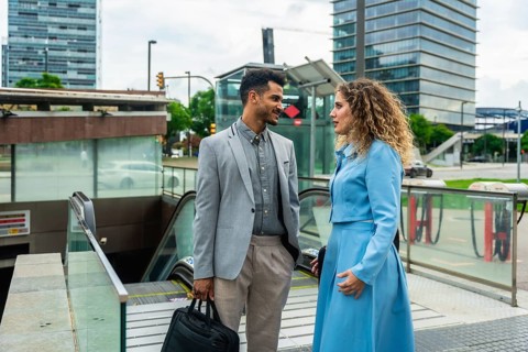 Two business colleagues having a casual conversation while standing near the entrance to an urban