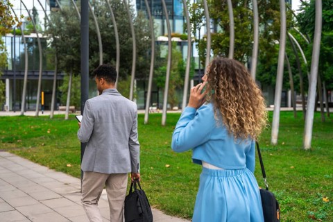 Two diverse business colleagues, a man texting on his smartphone and a woman conversing on hers,