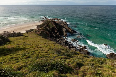 Sunlit daytime view with lookout platform below and glowing cliffs at Cape Byron, New South Wales,