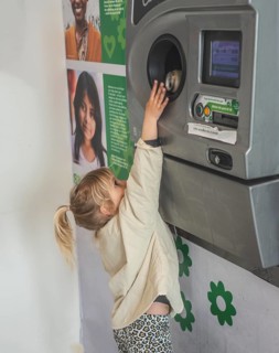 Blond girl, 5 years old, earns pocket money by recycling cans in recycling machine in Ystad, Skåne