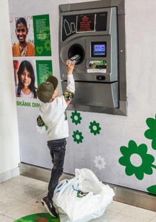 Boy, 7 years old, earns pocket money by recycling cans in recycling machine in Ystad, Skåne County,