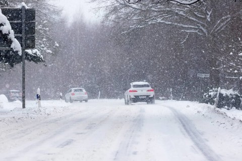Road traffic in winter, cars driving on heavily icy roads covered with snow and black ice in