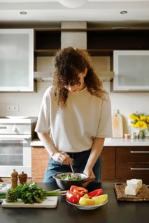 Woman mix grated goat cheese and chopped cilantro into a bowl in the kitchen