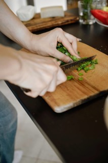 Unrecognizable woman chopping cilantro on wooden cutting board