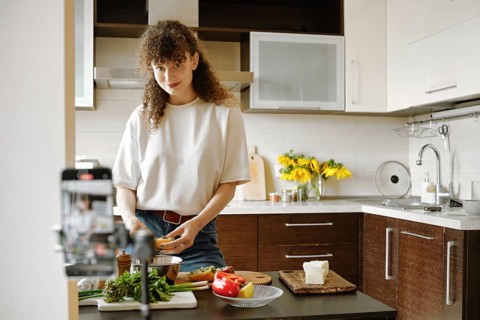 Joyful woman preparing healthy food in a modern kitchen and recording video recipe