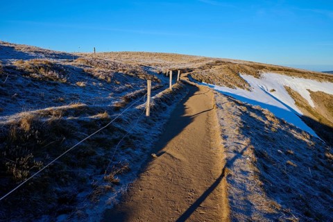 A frosty trail leads into the wintry expanse, accompanied by blue skies, winter, Route de Cretes,