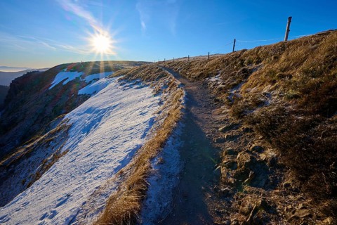 Path along a snowy mountainside at sunrise with frosty atmosphere, winter, Route de Cretes,