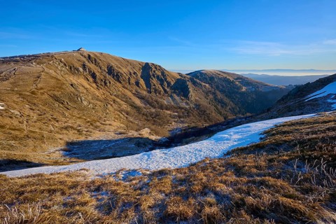 Extensive valley in the mountains, snowy, with clear skies and morning light, winter, Route de