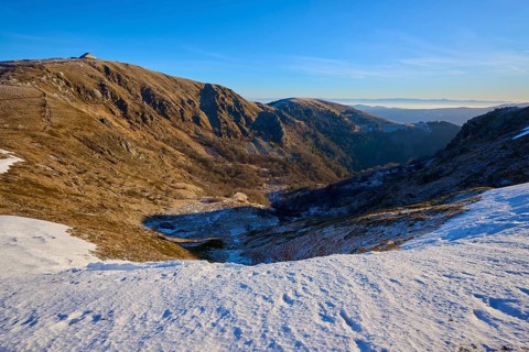 Deep snowy valley in the mountains with clear blue sky in the distance, winter, Route de Cretes,