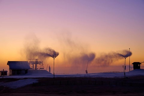 Under a dramatic sunset sky, snow cannons blow smoke across the empty hill, Winter, Route de