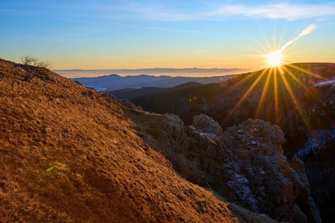 View over a sunlit rock edge in a vast mountain landscape, looking towards the Rhine Valley,