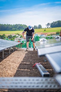 A technical worker installs solar panels on a construction site with a rural background, new Park