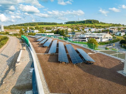 Solar systems on a flat roof with wide green areas and buildings in the background, new Park and