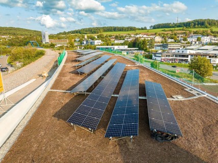 Solar module field in an urban environment with green landscape in the background, new park and