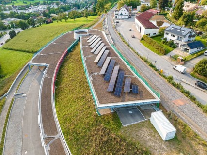 House roof with several solar panels surrounded by green landscape, new park and ride parking