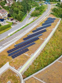 Solar system on a green roof next to railway tracks with urban surroundings, new park and ride