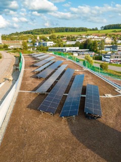 Solar panels on a hill roof with a view of rural surroundings and buildings, new park and ride