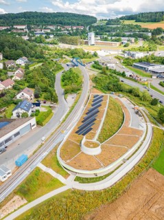 High view of a hilly landscape with solar panels and surrounding residential buildings, new Park