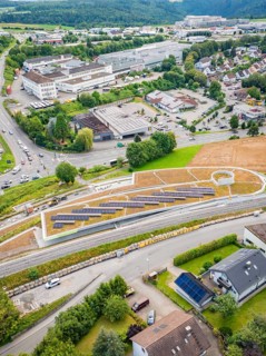 Overview of solar panels on a hill in an urban area with surrounding roads, new park and ride