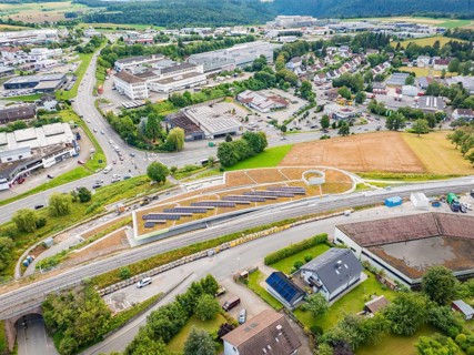 City panorama with solar systems on a hill in the middle of industrial buildings, new park and ride