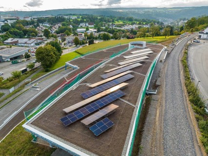 Expanded solar system on a roof with a view of a green landscape and city, new park and ride